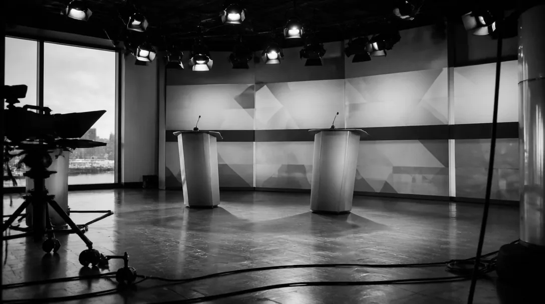 Tom debattstudio med två talarstolar i motljus, svartvitt
